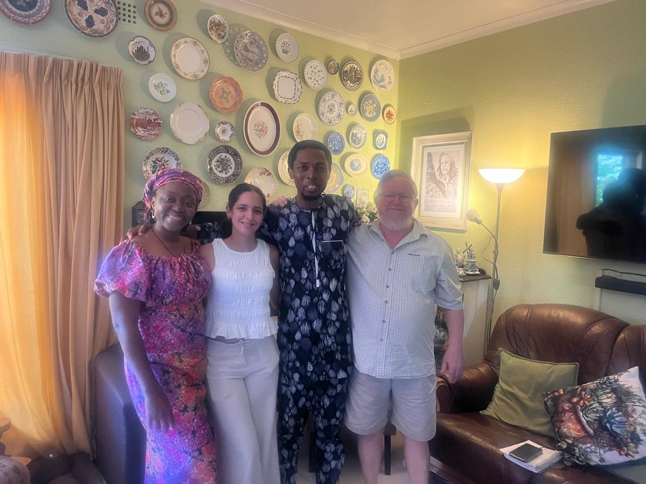 Grace, a young sister, John Damilola and a brother posing in front of the plate wall