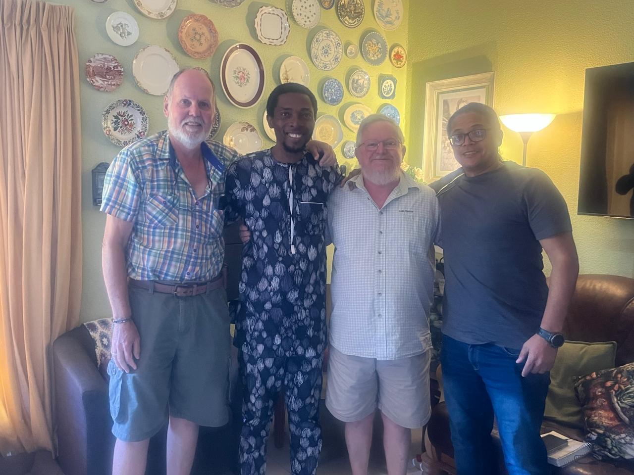 John Damilola standing with three brothers in front of the decorative plate wall