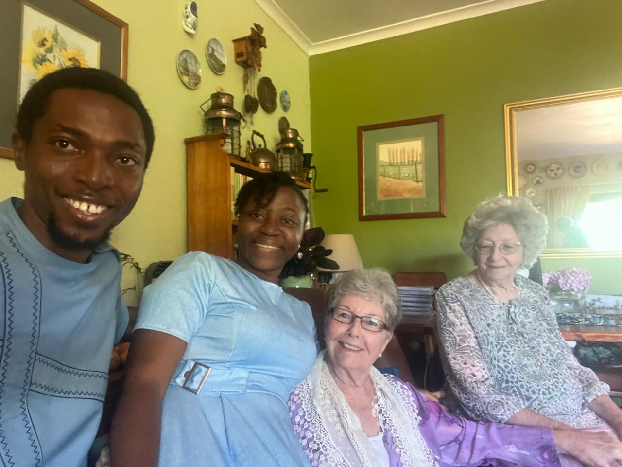 John and Grace Damilola seated with two elderly sisters on a green lounge sofa
