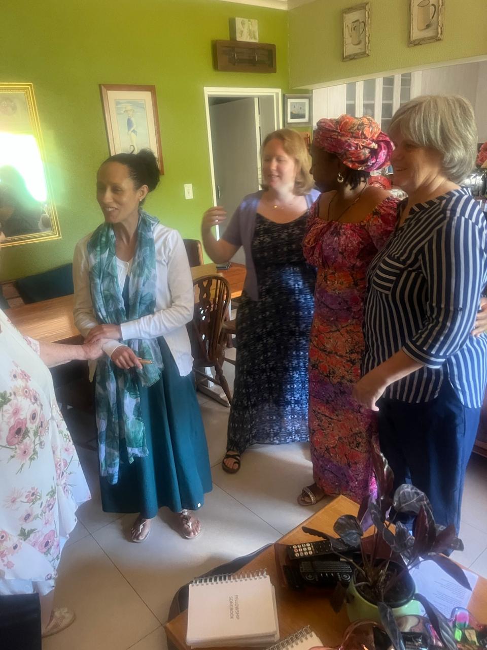 Sisters greeting each other warmly in a green lounge after a fellowship meeting