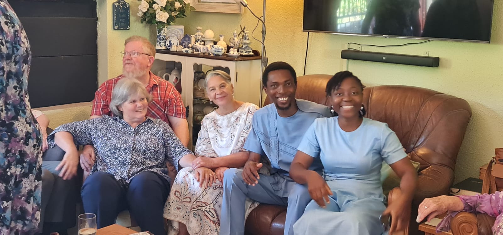 John and Grace Damilola with brothers and sisters gathered around a dining table in a living room, smiling together
