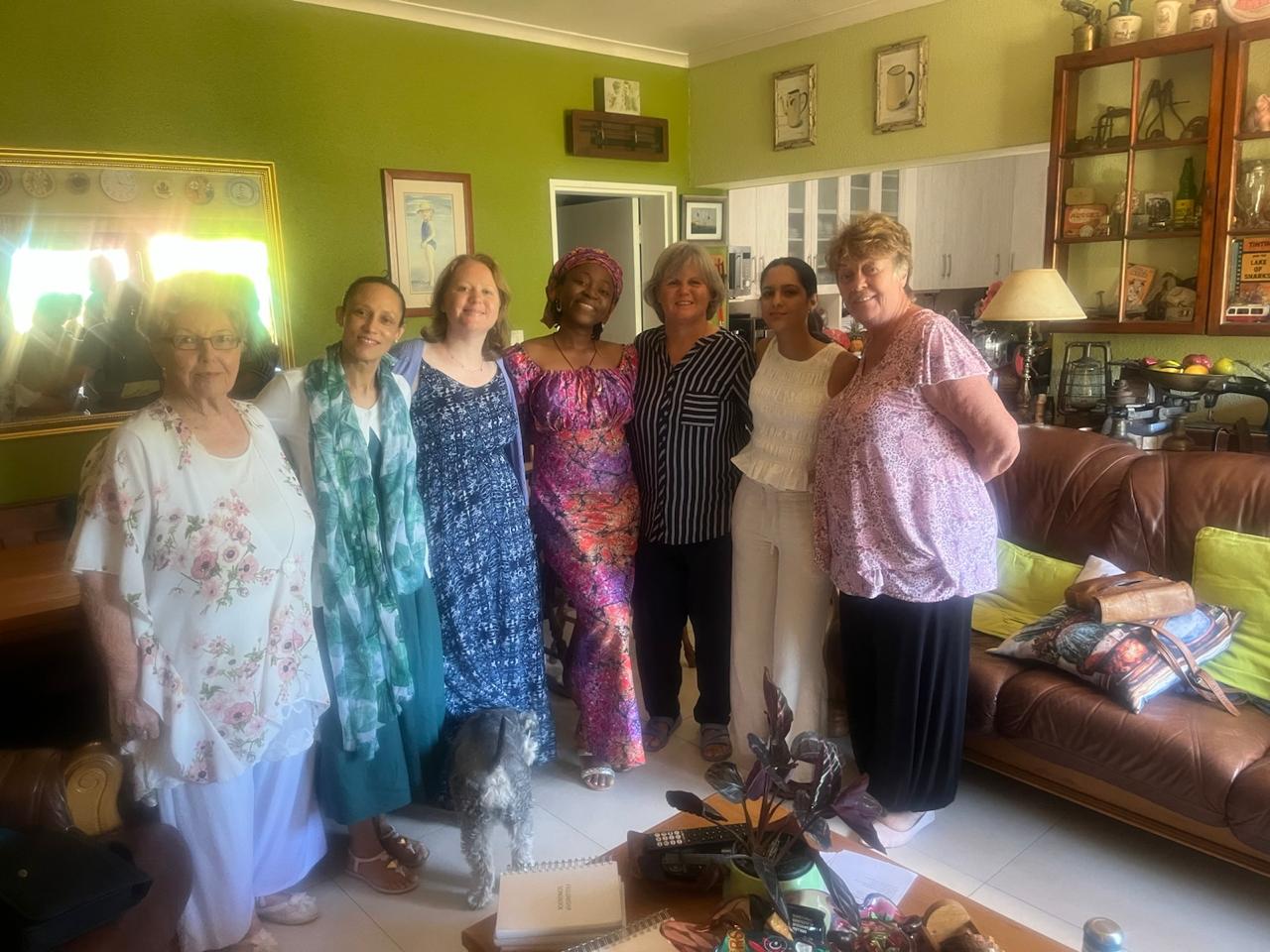 A group of sisters gathered in the lounge with a small dog at their feet